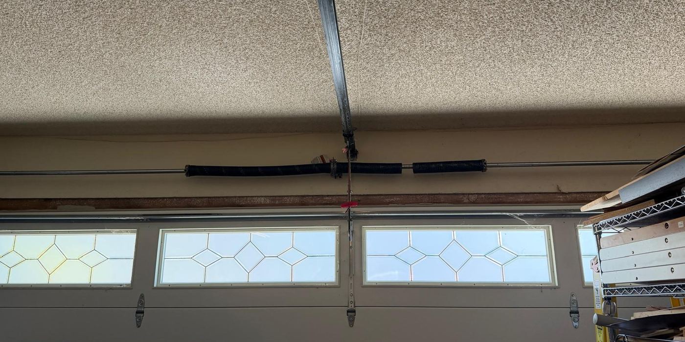 Worn short black torsion springs on a San Diego garage door before replacement